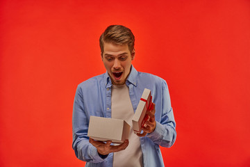 A guy with a beard happily looks into an open white box with a red bow.