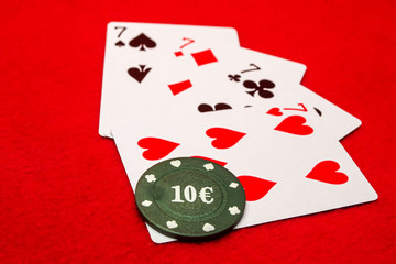 Four sevens and poker chip on a red background