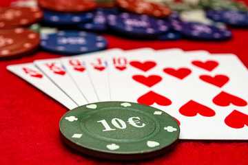 Poker chips and cards on red background
