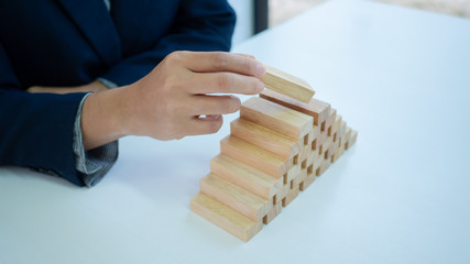 Businessman hand is placing the wooden pieces. Pyramid shape. Business development concept