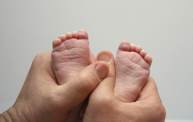 Tiny baby feet in caring male hands close-up