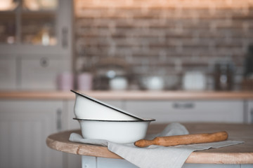 Vintage cooking bowls with rolling pin on kitchen table closeup. Rustic style.