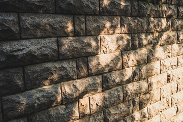 Background stone wall with patches of sunlight, light and shadow, solar hares, stone wall sun