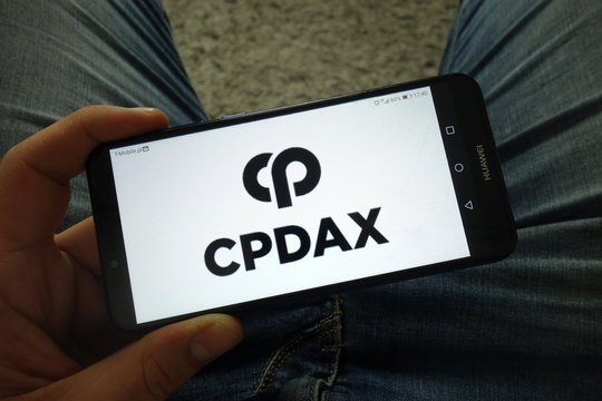 KONSKIE, POLAND - March 31, 2019: Man holding smartphone with Cpdax cryptocurrency exchange logo