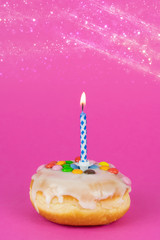 Delicious birthday cake with a burning candle, pink background with copy space