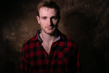 Portrait of good looking man with blue eyes and lumberjack shirt looking at camera with room for copy