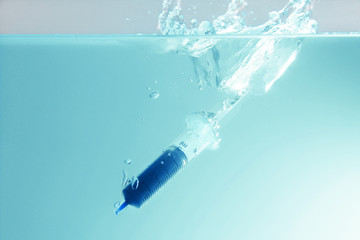 Environmental Pollution Concept.The syringe drop into water.Plastic pollution.Trash drop to the sea. Hazardous waste