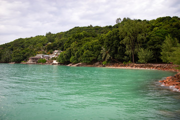 Seychelles islands shore line. Green water and cloudy sky