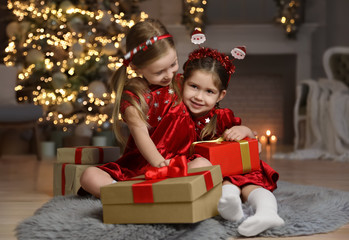 Fototapeta na wymiar Cute little children with Christmas gifts in living room