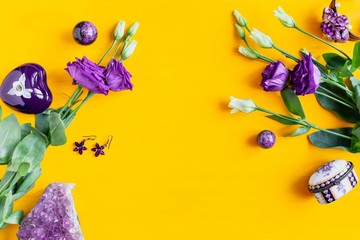 Purple flowers and women's accessories and jewelry on a yellow wooden background