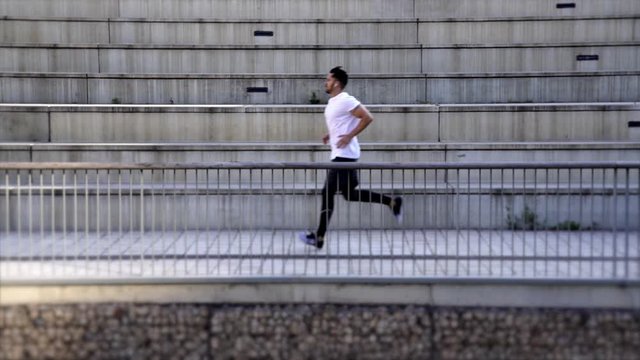 Full length of young 30 years old male jogger in activewear training outdoors in city keeping active lifestyle and shape in athletics. Men athlete running against urban setting background