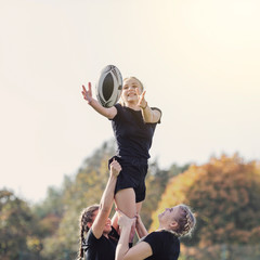 Girl catching a ball helped by her team mates