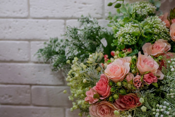 Artificial bouquet of flowers. Bouquet of mixed flowers in the stylish flower shop with white brick wall.