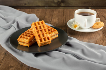 Belgian waffles in a black platter and a cup of tea