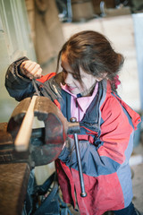 little girl works with file a wood in carpenter workshop