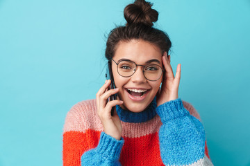 Image of shocked young woman in eyeglasses talking on smartphone