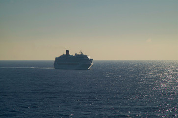 White modern cruiseship or cruise ship liner at sea with blue ocean and sky