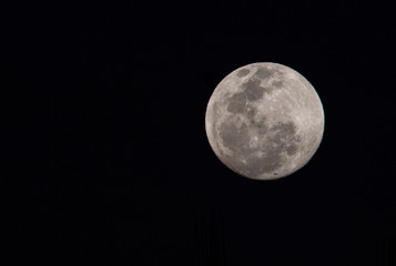 The full moon looks out from behind a building in Medellín