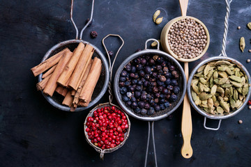 Set of spices over rustic metal background. Pink peppercorn, cardamom pods, juniper berries, coriander seeds and cinnamon sticks.