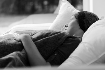 Thoughtful woman battling with tumor lying in hospice bed