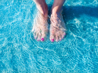 Feet of girl in the sand of the sea