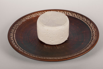Fototapeta na wymiar White round cheese in a brown platter