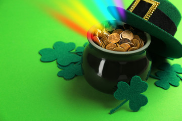 Pot with gold coins, hat and clover leaves on green background, space for text. St. Patrick's Day...