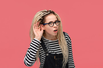 Young woman bending forward holding hand close to ear to hear important information.