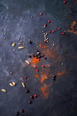 Scattered spices over rustic metal background. Pink peppercorn, cardamom pods, juniper berries, coriander seeds.