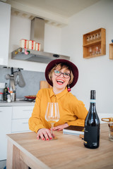 Adult woman indoor at home tasting wine laughing