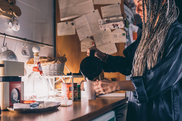 Mid adult woman indoor at home preparing a cup of hot tea