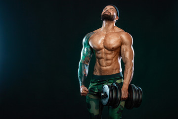 Fototapeta na wymiar Man athlete bodybuilder. Muscular young fitness sports guy doing workout with dumbbell in fitness gym