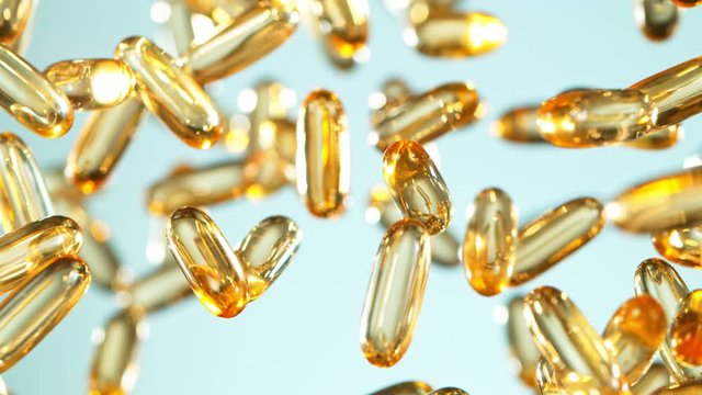Super Slow Motion Shot of Flying Golden Capsules on Gradient Background at 1000fps.