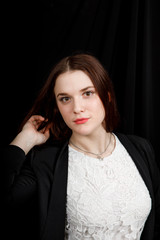 Portrait of young business woman in 
a black jacket on black background
