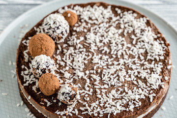 chocolate cake on a plate. Chocolate and coconut cake on a white wooden background. Foodfoto in a high key. Raw dessert