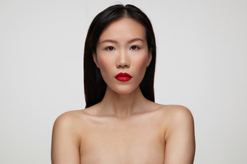 Closeup of pretty young brunette female with festive makeup keeping her red lips folded while...