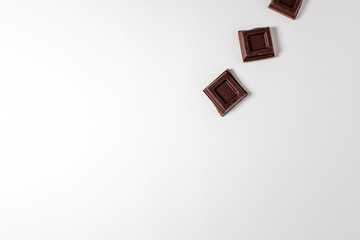 Dark chocolate pieces isolated on white background. Top view.