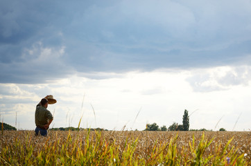 Farmer in straw hat stands at harvest ready wheat field
