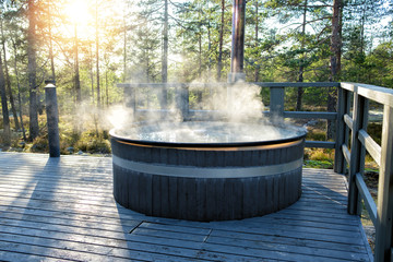 Modern big barrel outdoor hot tub in the middle of forest. The hot tub's soothing warm water relaxes muscles and eases tensions, so your worries can simply melt away.