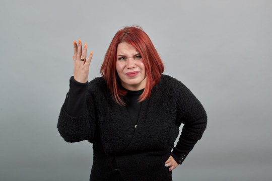 Young Redhead Fat Girl In Black Sweater On Grey Background Grumpy Woman Waves Her Hands