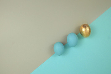 Flat style Easter egg of blue and gold color. Top view, located diagonally on a blue and beige background.