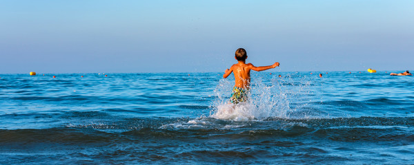 Child has fun and relaxes with the waves of the sea.