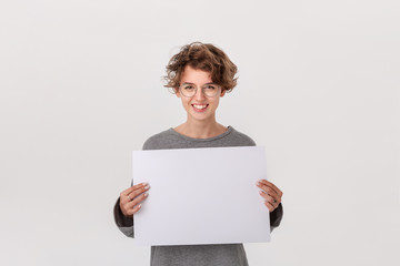 Smiling young woman with eyeglass holding empty blank paper board with copy space for text.