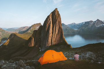 Camping in Norway man traveler relaxing in mountains with tent travel adventure healthy lifestyle active summer vacations sunset Segla mountain peak view