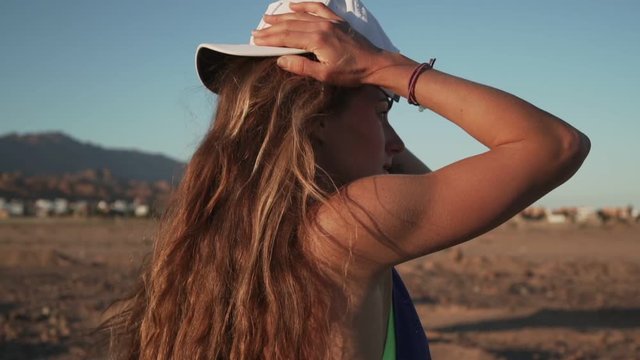 Sporty girl putting cap on her head in mount nature at sunset rapid slow motion