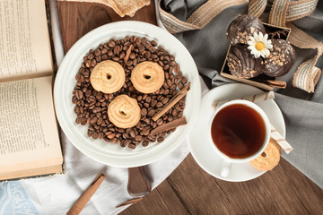 Coffee beans and biscuits in a saucer with a cup of tea