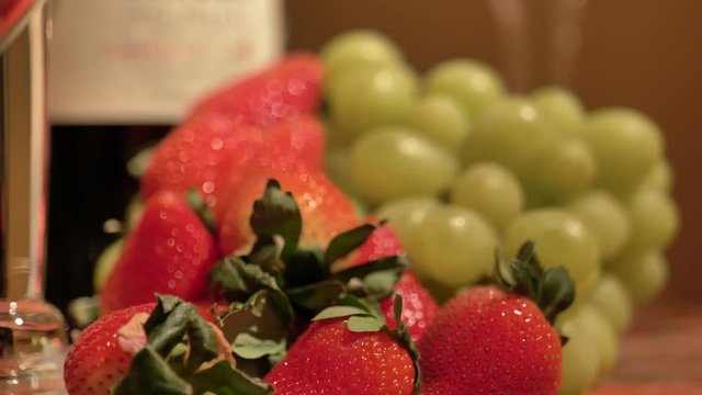 Strawberries and grapes next to wine bottle rack focus