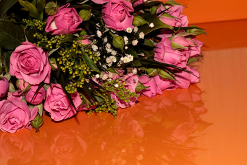 Green bouquet with small roses on an orange background. Pink small roses.