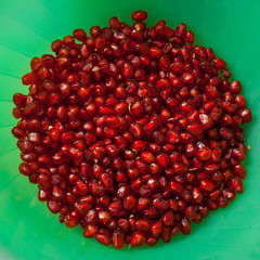 Ruby pomegranate seeds isolated in a circle on a green background