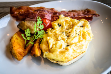 truffle egg with bacon strips and potato wedges on white plate